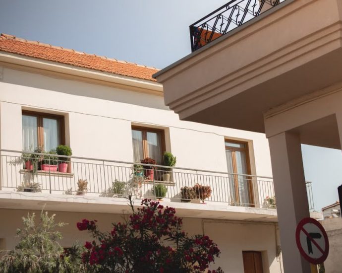 Traditional Greek house facade with potted plants and balcony details.
